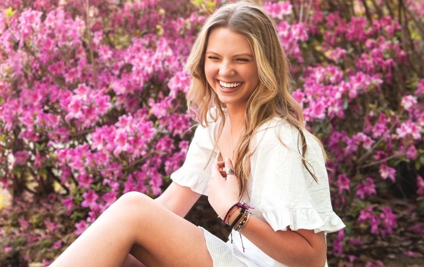 Teen senior girl laughing in pink flowers